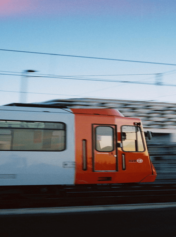 Side view of an orange and white train speeding with motion blur.